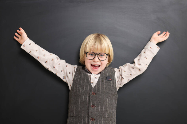 Emotional little school child in uniform near chalkboard - Фото, изображение