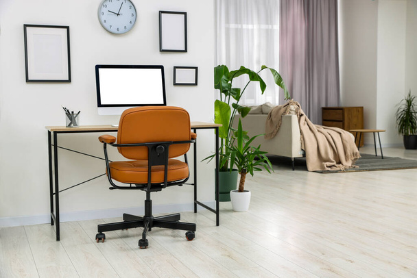 Stylish room interior with comfortable office chair, desk and houseplants - Fotó, kép