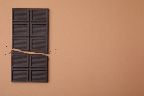 Broken chocolate bar on brown background, top view. Space for text - Foto, imagen