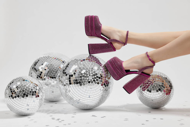 Woman in pink high heeled shoes and disco balls on white background, closeup - Photo, image