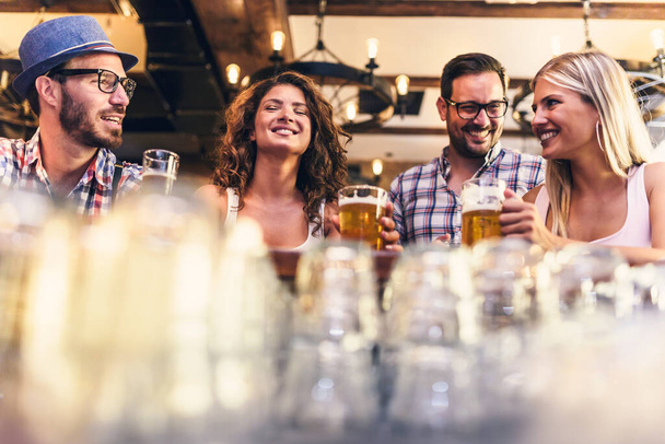веселые друзья проводят время в баре, пьют пиво - Фото, изображение