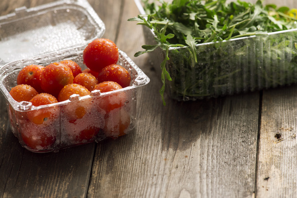 cherry rajčata v plastové nádobí a rukolou - Fotografie, Obrázek