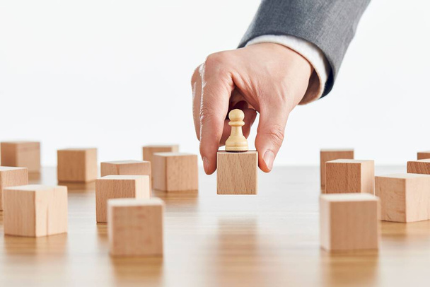 A businessman holding a wooden block with chess pawn figure on it-business concept - Foto, afbeelding