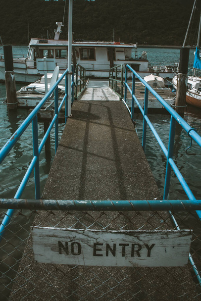 A vertical shot of NO ENTRY sign on the dock with blue railings - Foto, afbeelding