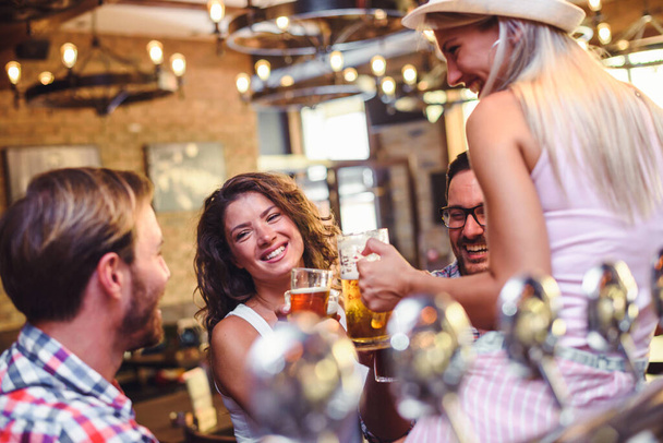 cheerful friends spending time in bar, drinking beer - Foto, Imagen