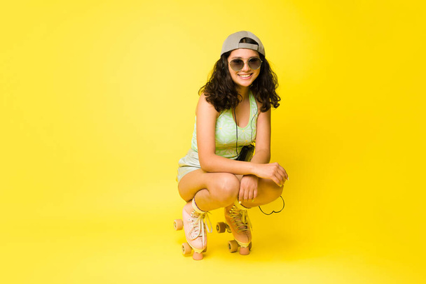 Adorable niña adolescente de trece años patinando sonriendo usando patines vintage y divirtiéndose con gafas de sol de verano  - Foto, Imagen