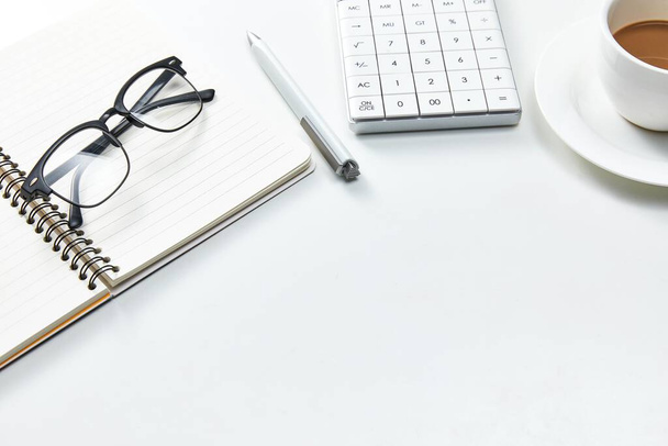 A top view of a white office table with a notebook, glasses and a cup of coffee - Foto, immagini