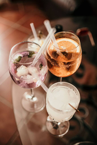 A vertical closeup shot of three glasses of drinks placed on a glass table - Foto, afbeelding