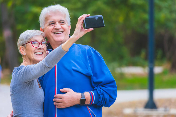 Lächelndes Senioren-Paar macht Selfie im Park - Foto, Bild