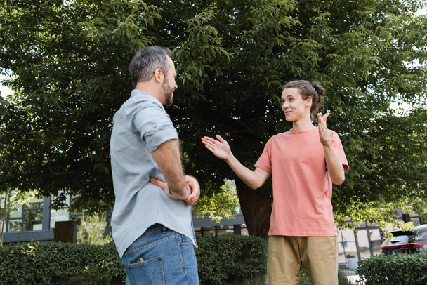šťastný dospívající chlapec ukazuje velké gesto s rukama v blízkosti vousatý otec v parku  - Fotografie, Obrázek