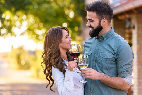 junges Paar trinkt Wein im Weinberg  - Foto, Bild