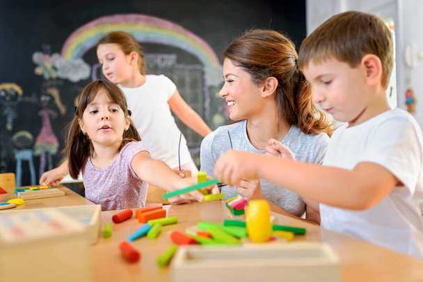 nauczyciel bawiący się z dziećmi w przedszkolu za pomocą drewnianych klocków - Zdjęcie, obraz