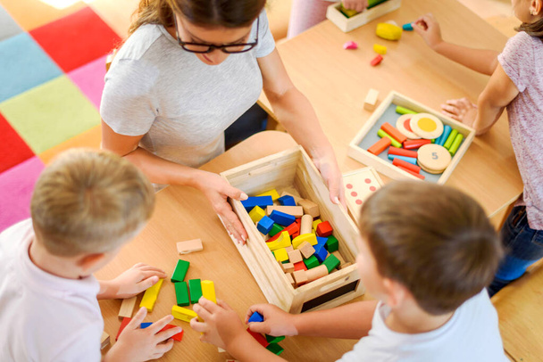 teacher playing with kids in kindergarten using wooden blocks - Φωτογραφία, εικόνα