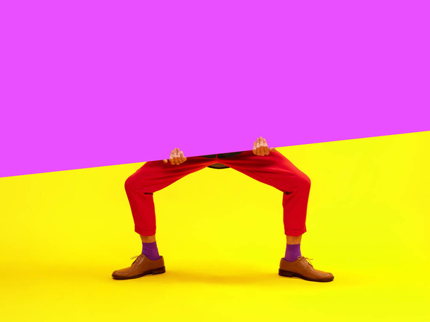 Male legs in red pants and classical shoes over bright yellow and purple background. Empty space for ad, text, poster. Concept of art, creative vision, fashion. Complementary colors. - 写真・画像