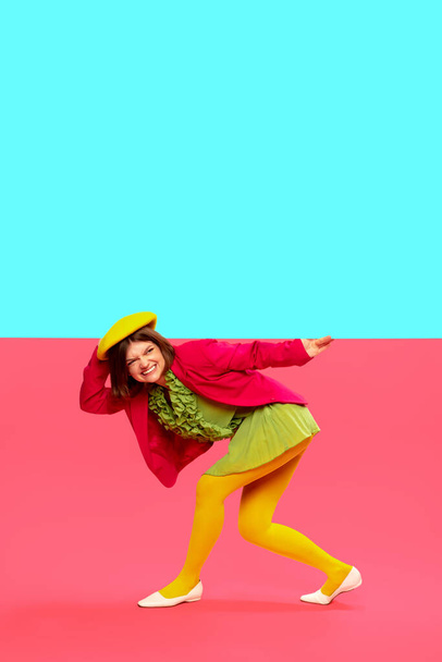 Challenges and difficulties. Young stylish girl in colorful clothes over vivid blue and pink background. Pop art style. Art, creative vision, fashion concept. Complementary colors. Copy space for ad - Foto, imagen