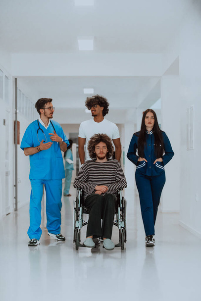 Dwóch lekarzy i pielęgniarka idący korytarzem szpitalnym, pchający pacjenta na wózku inwalidzkim. Personel medyczny zapewniający opiekę i opiekę nad pacjentem. - Zdjęcie, obraz
