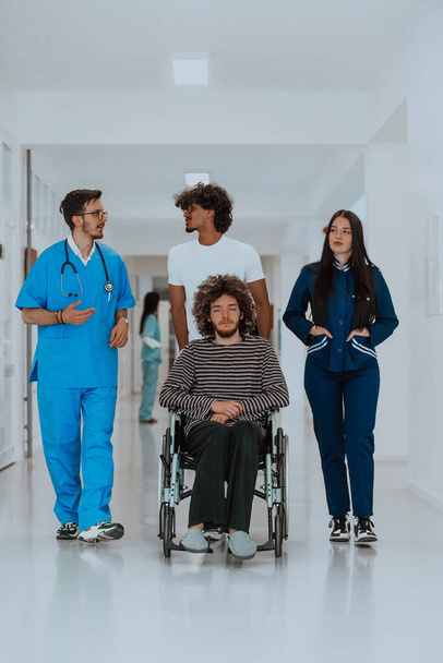 Két orvos és egy nővér sétál végig a kórház folyosóján, tolószékbe taszítva egy beteget. A beteget gondozó és odafigyelő egészségügyi szakemberek. - Fotó, kép