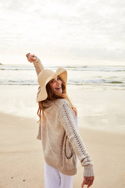 Mindig jól érzem magam a parton. Portré egy fiatal nőről, aki kinyújtott karokkal áll a parton. - Fotó, kép
