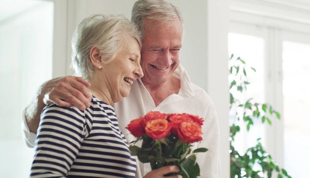 Ty jesteś miłością mojego życia. starszy mężczyzna rozpieszcza swoją żonę różami w domu - Zdjęcie, obraz