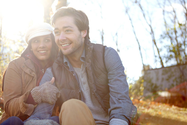 Enjoying a carefree afternoon. A happy young couple sitting together outdoors in the woods - Foto, Imagem