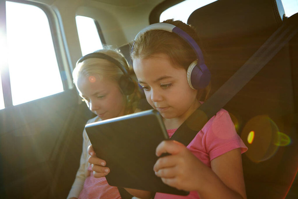 Technological travel packs for kids. a two little girls traveling in a car - Φωτογραφία, εικόνα
