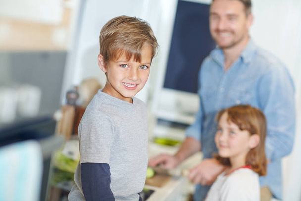 Ich liebe es, wenn Papa für uns kocht. Porträt eines entzückenden kleinen Jungen, der mit seinem Vater und seiner Schwester in der Küche steht - Foto, Bild