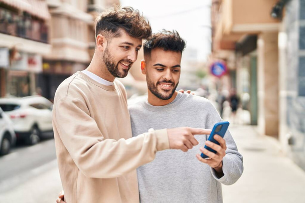 Casal jovem usando smartphone abraçando uns aos outros na rua - Foto, Imagem
