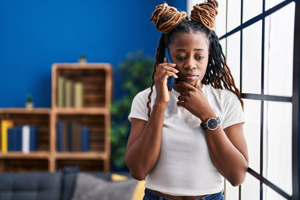 Африканская американка разговаривает на смартфоне, стоя дома - Фото, изображение