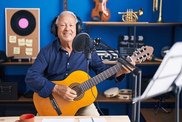 Senior grey-haired man musician singing song playing guitar at music studio - Zdjęcie, obraz