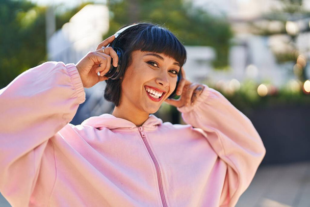 Молода жінка посміхається впевнено слухаючи музику в парку
 - Фото, зображення
