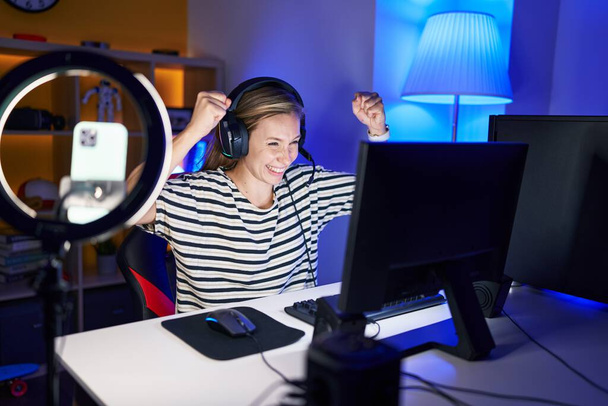 Fiatal szőke nő streamer videojáték a győztes kifejezés a játékteremben - Fotó, kép