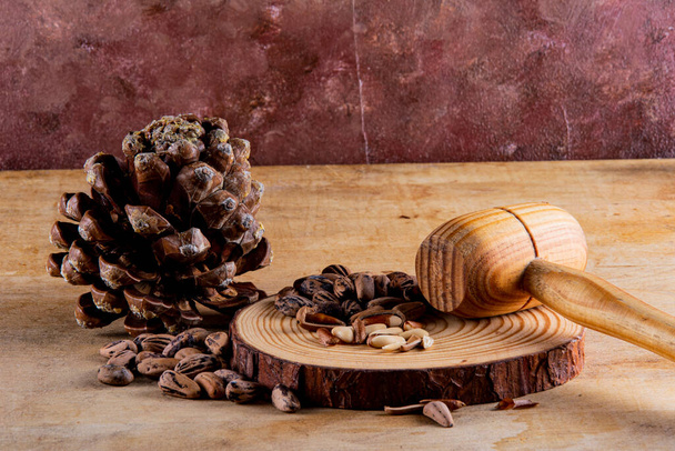 Breaking pine nuts on a board with a wooden mace. Rustic and warm atmosphere. - Foto, Imagem