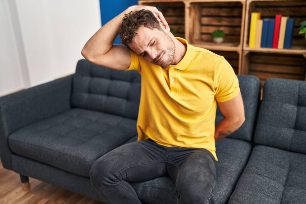 Young hispanic man suffering for backache sitting on sofa at home - Photo, Image