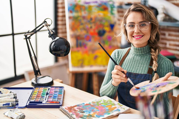 Sanat stüdyosundaki masanın üzerine çizim yapan genç bir kadın sanatçı. - Fotoğraf, Görsel