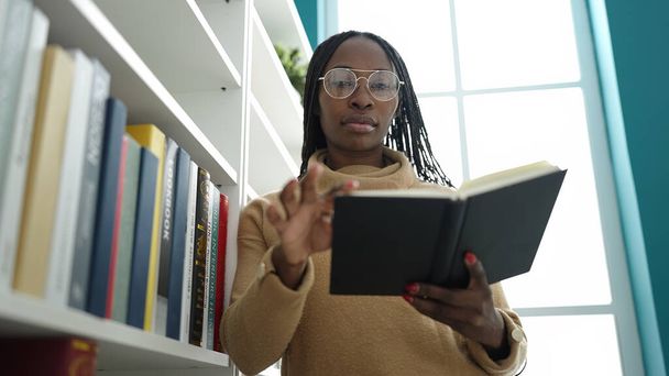 Mujer africana leyendo un libro en la universidad de la biblioteca - Foto, imagen
