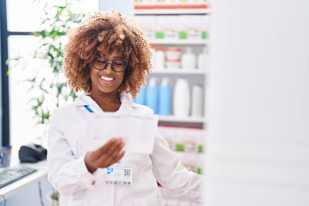 African american woman pharmacist reading prescription at pharmacy - Photo, Image