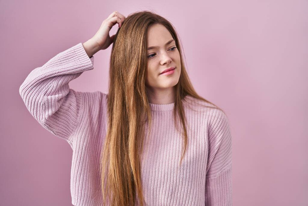 Young caucasian woman standing over pink background confuse and wondering about question. uncertain with doubt, thinking with hand on head. pensive concept.  - Photo, Image