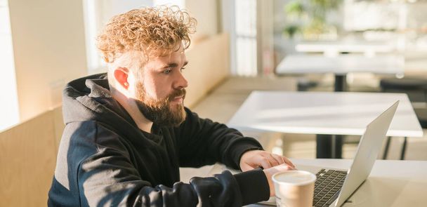 Kafeteryada dinlenen beyaz bir erkek sosyal ağlarda sohbet ediyor yetenekli bir serbest yazar bilgisayarında web günlüğü için yazı yazmanın keyfini çıkarıyor. - Fotoğraf, Görsel