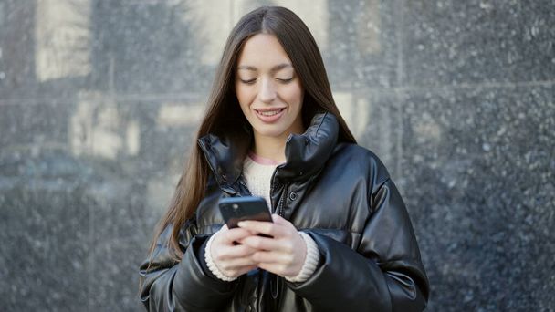 Nuori kaunis latino nainen hymyilee luottavainen käyttämällä älypuhelin kadulla - Valokuva, kuva