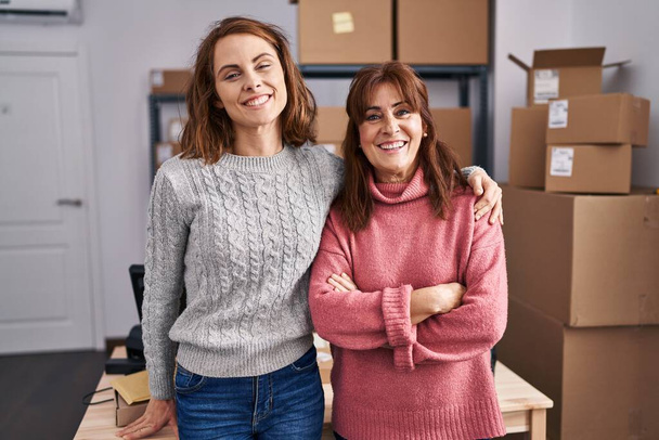 Due donne che lavorano alla piccola impresa e-commerce guardando positivo e felice in piedi e sorridendo con un sorriso fiducioso mostrando denti  - Foto, immagini