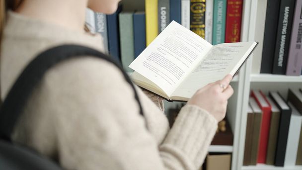 Joven estudiante rubia leyendo libro en la biblioteca de la universidad - Foto, imagen