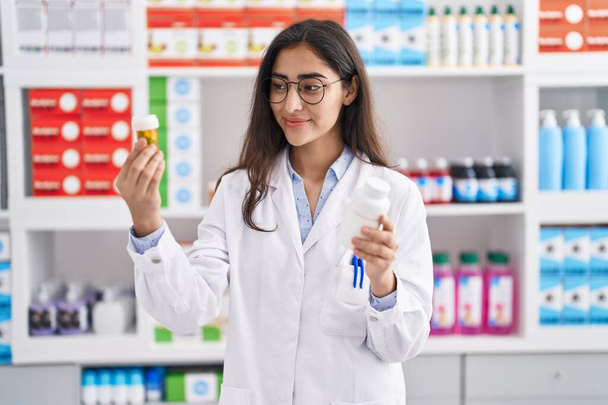 Young hispanic girl pharmacist choosing pills at pharmacy - Foto, Bild