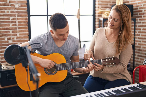 Man and woman musicians having classic guitar lesson at music studio - Foto, afbeelding