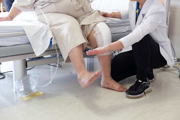 Médico fazendo fisioterapia para paciente com uma lesão no joelho
 - Foto, Imagem