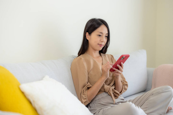 Mujer uso del teléfono móvil y sentarse en el sofá - Foto, Imagen