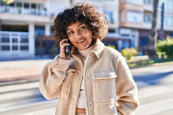 Young beautiful hispanic woman smiling confident talking on the smartphone at street - Fotó, kép