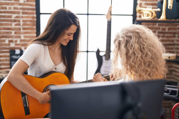 Δύο γυναίκες μουσικοί που έχουν μάθημα κλασικής κιθάρας στο στούντιο μουσικής - Φωτογραφία, εικόνα