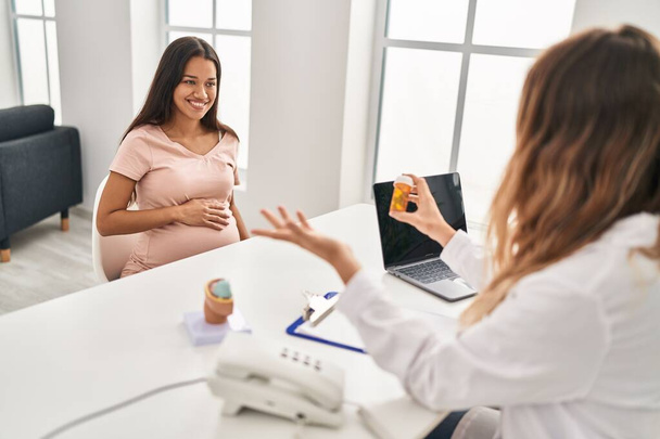 Young latin woman pregnant patient having medical session at clinic - Foto, afbeelding