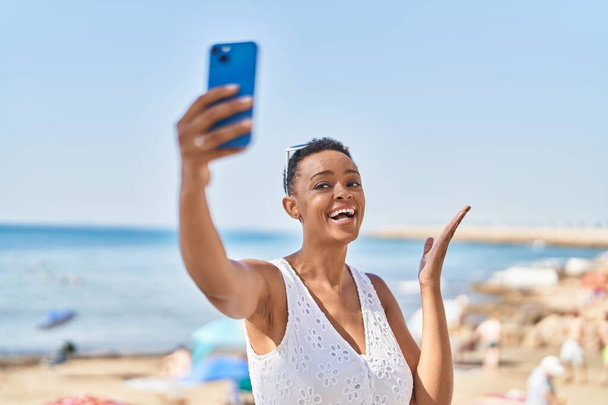 afro americano donna sorridente fiducioso avendo video chiamata a mare - Foto, immagini