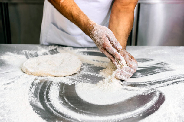 Pétrissage de la pâte : Gros plan sur les mains farineuses d'un boulanger - Photo, image